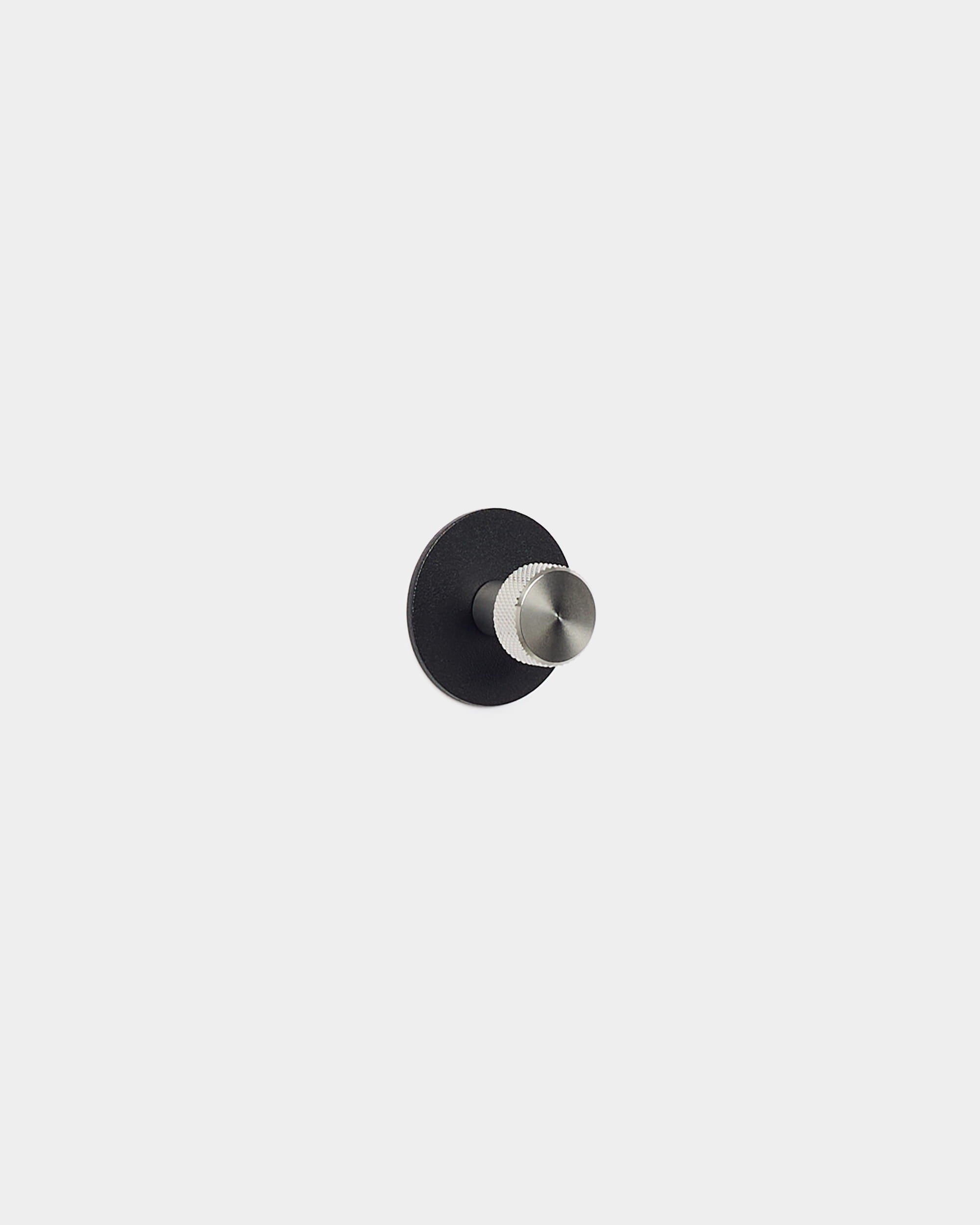 Norr Coat Hook fra WoodUpp har en rund, sort base og en sølvfarvet pind, der er designet som tilbehør til Akupanel-akustikpaneler og passer til minimalistiske, nordiske rum.